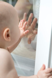 Baby sucht Mutterhand hinter Glasscheibe, Portrait Baby sucht Mutterhand hinter Glasscheibe, Portrait
